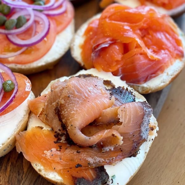 Close-up of three bagels with cream cheese, smoked salmon, tomatoes, red onions, and capers.