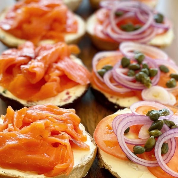 Close-up of bagels with cream cheese, smoked salmon, tomato, red onion, and capers.