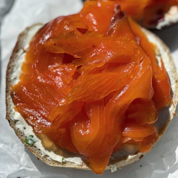Close-up of a bagel with cream cheese and a generous topping of bright orange smoked salmon.